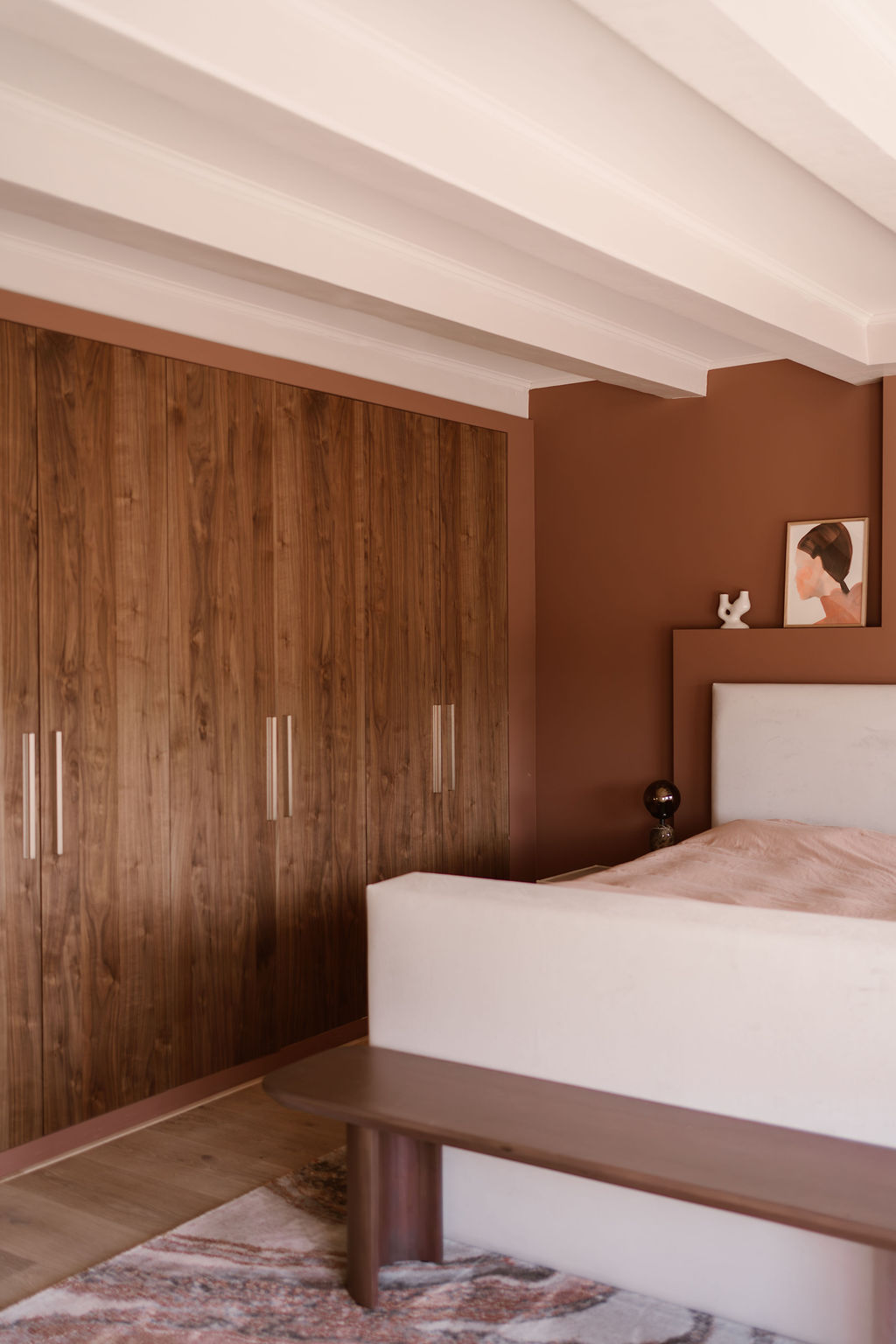 Sfeervolle slaapkamer met warme kleuren en notenhouten kastdeuren. 